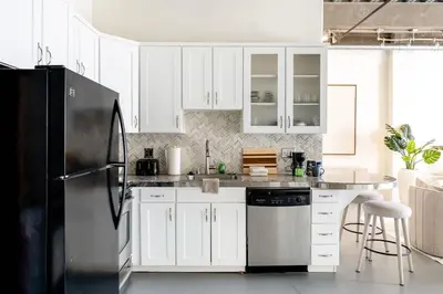 a kitchen with white cabinets and a black refrigerator at DTLA Boutique Loft w Rooftop Pool Hot Tub in Los Angeles
