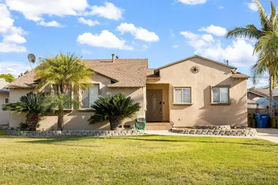 a house with palm trees in front of it at Family Oasis Near Disneyland & Knotts in Downey