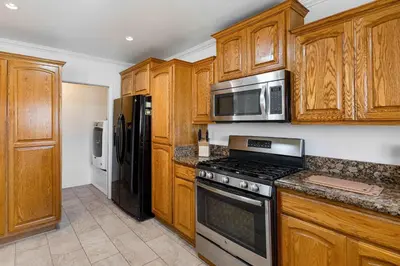 a kitchen with wooden cabinets and stainless steel appliances at Family Oasis Near Disneyland & Knotts in Downey