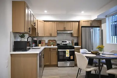 a kitchen with wooden cabinets and a table with chairs at Luxe Ensuite in Shared Home-Minutes to USC in Los Angeles