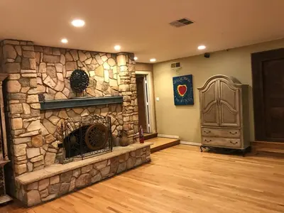 a stone fireplace in a living room with a wooden floor at Family Nature Retreat Near LA with Indoor Grotto Pool in Simi Valley