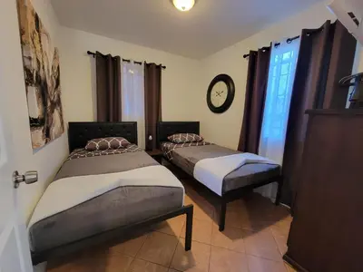 two beds in a room with a clock on the wall at 2BR Guest Suite With Parking and Garden in Pico Robertson Near Beverly Hills and Cedar Sinai in Los Angeles