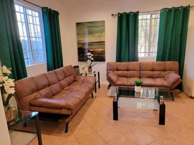 a living room with brown leather couches and green curtains at 2BR Guest Suite With Parking and Garden in Pico Robertson Near Beverly Hills and Cedar Sinai in Los Angeles