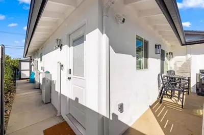 a white building with a door and a chair on a patio at Luxury 1BR Suite Kitchen, Fireplace, Laundry, BBQ in Simi Valley