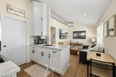a kitchen with white cabinets and a living room at Luxury 1BR Suite Kitchen, Fireplace, Laundry, BBQ in Simi Valley