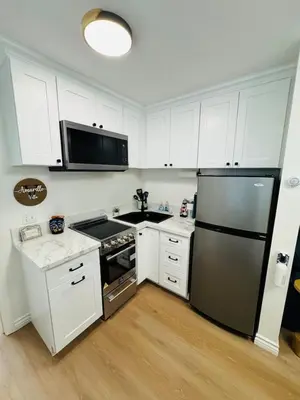 a kitchen with white cabinets and a stainless steel refrigerator at Cozy Villa with Spa, Fireplace, Kitchen, Yard, BBQ in Simi Valley