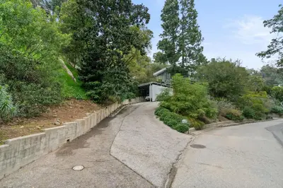 a road with a retaining wall next to a house at New Listing Modern Hollywood Hills Sanctuary by Colby & Conrad in Los Angeles