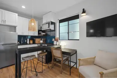 a kitchen with white cabinets and a table and chairs at Modern Luxe Studio in East Los Angeles in Los Angeles