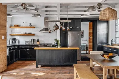 a kitchen with black cabinets and a wooden table at Elegant 3-bedroom home Retreat in East Los Angeles in Los Angeles