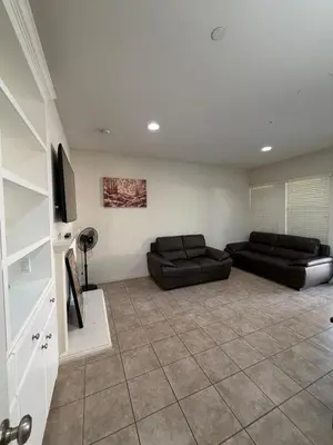 a living room with two black couches and a tv at Cozy 2-Bedroom Home in Eastvale in Corona