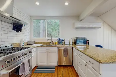 a kitchen with white cabinets and a stove top oven at Mountain Playhouse in Lake Arrowhead