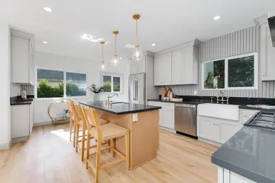 a kitchen with white cabinets and a island with chairs at Chic WeHo Retreat near Sunset Blvd in Los Angeles