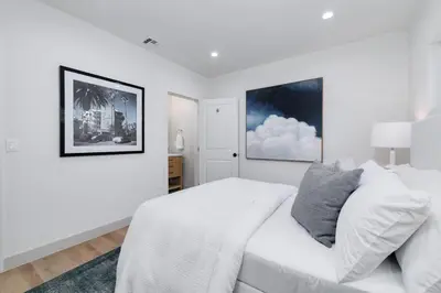 a white bedroom with a bed and two pictures on the wall at Chic WeHo Retreat near Sunset Blvd in Los Angeles