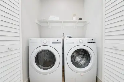 a white laundry room with a washer and dryer at Chic WeHo Retreat near Sunset Blvd in Los Angeles