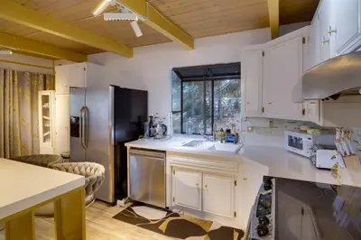 a kitchen with white cabinets and a stainless steel refrigerator at Outdoor Oasis in Pine Mountain Club! Cabin Getaway in Pine Mountain Club