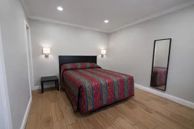 a bedroom with a bed and a mirror on the wall at Carlton Motel in Los Angeles