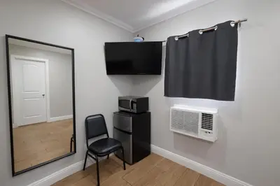 a room with a chair and a television and a window at Carlton Motel in Los Angeles