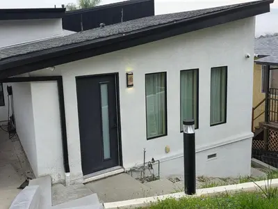 a white house with green windows and a black door at Private Studio City Suite Walk to Universal-15 min in Los Angeles