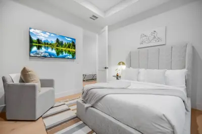 a white bedroom with a large bed and a chair at Colfax Estate in Los Angeles