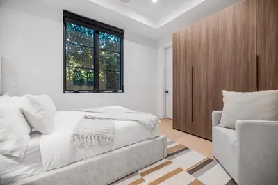 a white bedroom with a bed and a chair at Colfax Estate in Los Angeles