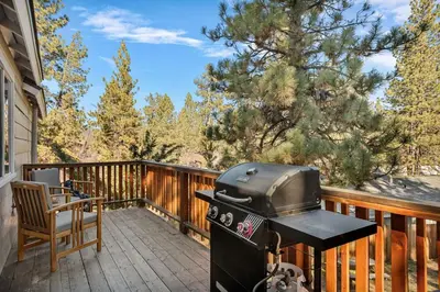 a grill on a deck with a table and a chair at Snuggle Down Cottage in Big Bear Lake