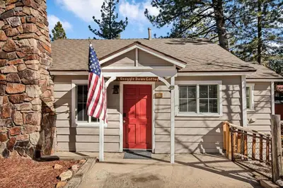 a house with a red door and an american flag at Snuggle Down Cottage in Big Bear Lake
