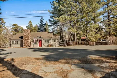 a house with a red door on a driveway at Snuggle Down Cottage in Big Bear Lake