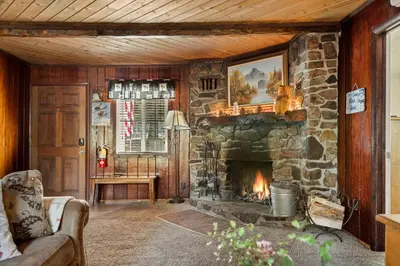 a living room with a stone fireplace and a couch at Snuggle Down Cottage in Big Bear Lake