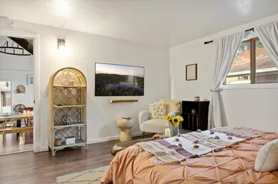 a bedroom with a bed and a chair in a room at The Willow Cabin in Big Bear Lake