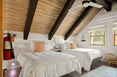 two beds in a room with wooden ceilings at The Willow Cabin in Big Bear Lake