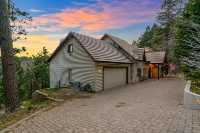 a house with a garage on a driveway at Vista Lodge! 20 min to Silverwood Lake in Cedarpines Park