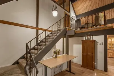 a room with a staircase and a wooden table at Vista Lodge! 20 min to Silverwood Lake in Cedarpines Park