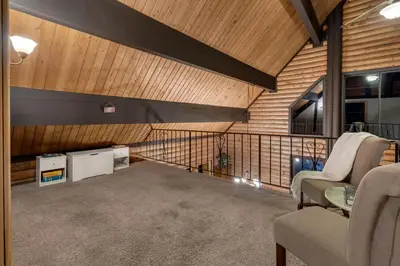 a room with two chairs and a balcony with wooden walls at Vista Lodge! 20 min to Silverwood Lake in Cedarpines Park