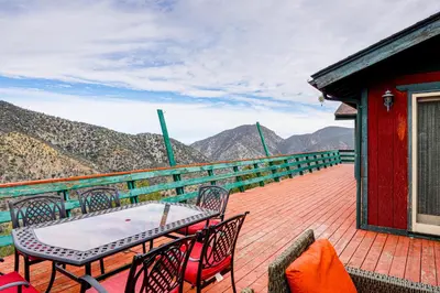 a table and chairs on a deck with mountains in the background at Private Sauna and Mtn-View Deck! Kern County Home in Pine Mountain Club