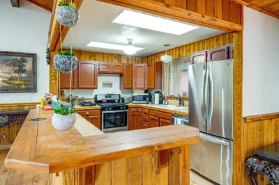 a kitchen with wooden cabinets and a stainless steel refrigerator at Private Sauna and Mtn-View Deck! Kern County Home in Pine Mountain Club