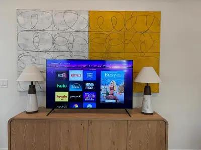 a flat screen tv sitting on a cabinet with two lamps at Modern Mid-Wilshire Escape Prime Spot in Los Angeles