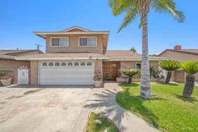 a palm tree in front of a house with a garage at Spacious 5 Bedroom Home Near Disneyland & Knotts with Jacuzzi Spa in Norwalk