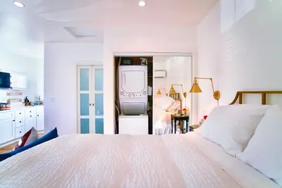 a white bedroom with a large bed and a tv at The Sycamore Suite in Santa Clarita