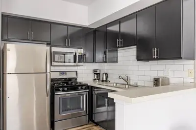 a kitchen with stainless steel appliances and black cabinets at Blueground Hollywood gym AC nr Runyon LAX-1344 in Los Angeles