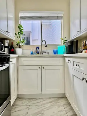 a kitchen with white cabinets and a sink and a window at Proper Stays at Melrose - West Hollywood Premium R suite in Los Angeles