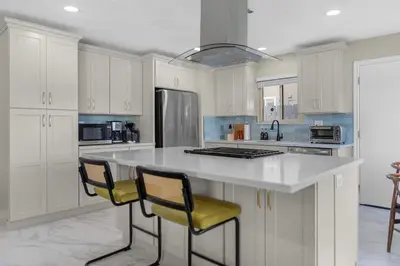 a kitchen with white cabinets and a large island with two chairs at Near LLU Hospital Calm 3BR Workspace in Loma Linda