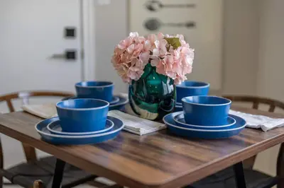 a table with blue cups and a vase with pink flowers at Near LLU Hospital Calm 3BR Workspace in Loma Linda