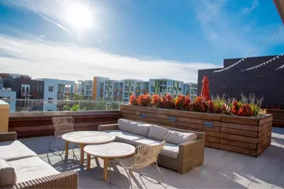 a rooftop patio with a couch and tables and flowers at Runway Playa Vista in Los Angeles