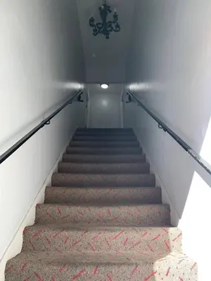 a stairway with a carpeted staircase with a chandelier at 1 bedroom spacious apt in Beverly hills in Los Angeles
