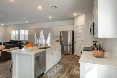 a kitchen with white cabinets and a living room at Pet-Friendly Yard! Family Home in Bakersfield in Bakersfield