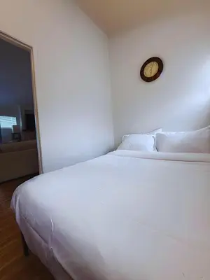 a white bed in a room with a clock on the wall at Mar Vista 2BR Retreat Office Huge Backyard in Los Angeles