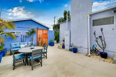 a patio with a table and chairs and a blue building at Mar Vista 2BR Retreat Office Huge Backyard in Los Angeles