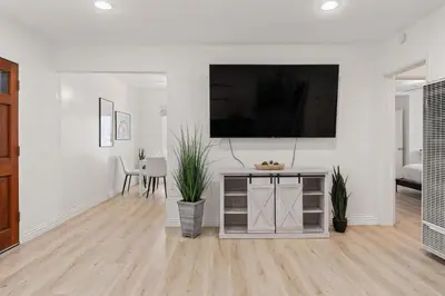 a white living room with a flat screen tv on a wall at Relax in Stylish 3BR with Fire Pit Gym and Parking in Los Angeles