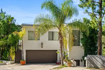 a palm tree in front of a house with a garage at Hillside Retreat Near Universal Studios & Hollywood Sign in Los Angeles
