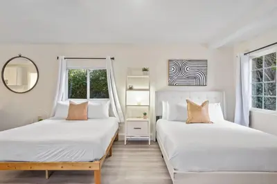 two beds in a white room with two windows at Luxe 6BR Retreat with Trampoline Swing and BBQ Grill in Los Angeles